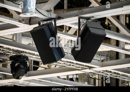 Powerful loudspeakers suspended on beams of supporting structures under the ceiling of a large arena Stock Photo