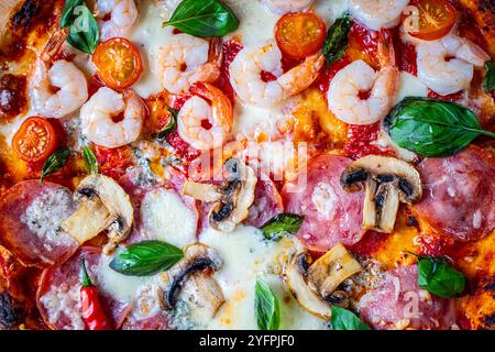 Pizza with two types of toppings: one half of pepperoni with mushrooms, the other with tomatoes and shrimp with cheese. Background with pizza texture. Stock Photo