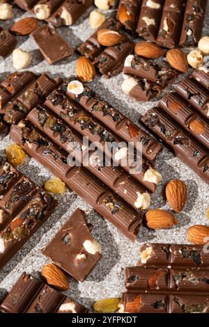 Broken chocolate pieces with nuts and raisins on a stone background top view Stock Photo