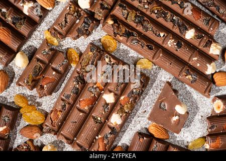 Broken chocolate pieces with nuts and raisins on a stone background top view Stock Photo