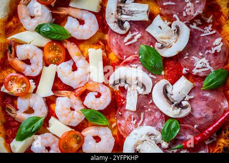 Pizza with two types of toppings: one half of pepperoni with mushrooms, the other with tomatoes and shrimp with cheese. Background with pizza texture. Stock Photo