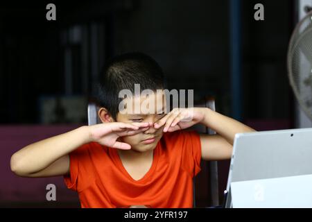 A focused boy engages with a laptop, showcasing curiosity and interaction with technology. The image captures the essence of learning and modern commu Stock Photo
