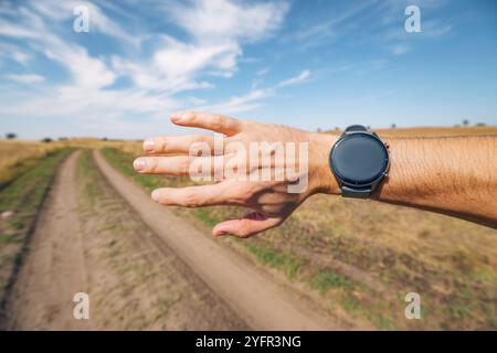Close-up of a young male runner checking his smartwatch while jogging in a natural setting Stock Photo