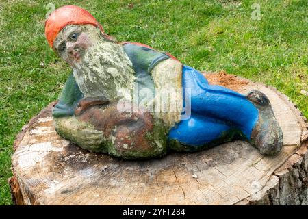 A garden gnome lying on tree stump Stock Photo