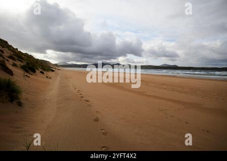 footprints in the sand and view of the sea at trawbreaga bay from five finger strand, inishowen peninsula, county donegal, republic of ireland Stock Photo