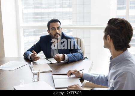 Serious confident Indian business owner man talking to male coworker Stock Photo