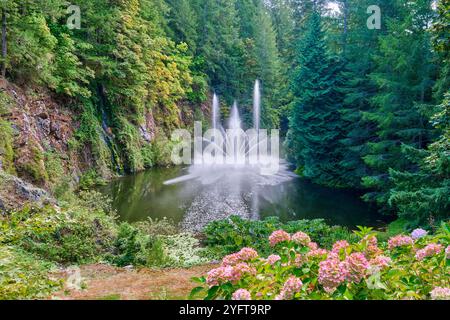 The Dancing Ross Fountain in a pond surrounded by lush trees in the Butchart Gardens on Vancouver Island. Stock Photo