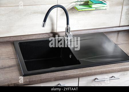 Black Ceramic Stone Kitchen Sink on light brown wooden table. Mock up, Copy space Sink Cleaner Eco friendly Concept Stock Photo