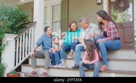 Multi Generation Family Sit On Steps Leading Up To House Porch Stock Photo