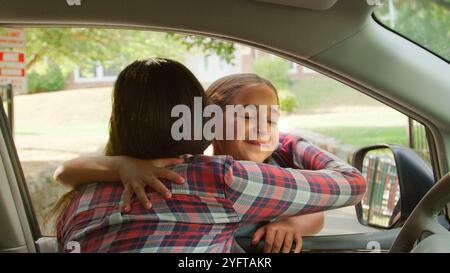 Daughter Hugging Mother In Car Dropping Her Off In Front Of School Gates Stock Photo