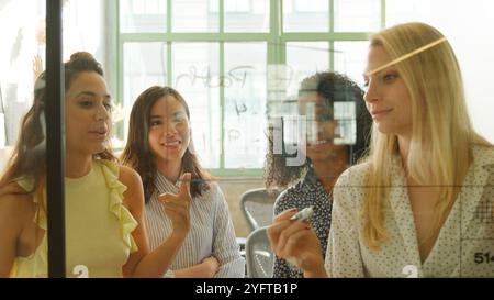 Female Business Team Meeting In Modern Office Writing Ideas On Glass Screen In Modern Office Stock Photo