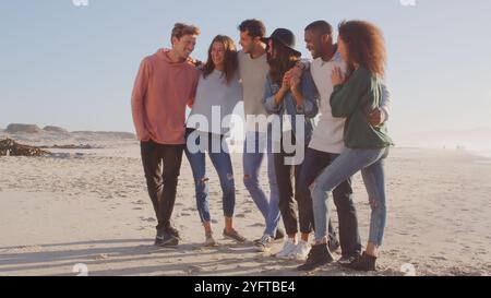 Group Of Casually Dressed Friends Having Fun Standing On Winter Beach Together Stock Photo