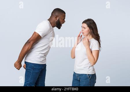 Angry afro guy emotionally shouting at his scared girlfriend, blaming her Stock Photo