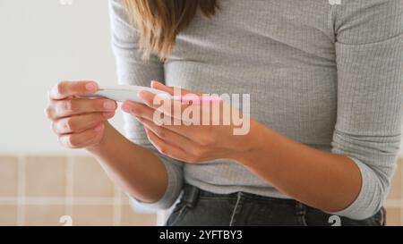 Close Up Of Woman In Bathroom Using Home Pregnancy Test Stock Photo