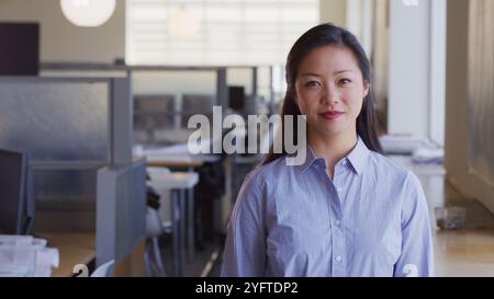 Portrait Of Smiling Businesswoman Working In Empty Open Plan Office Stock Photo