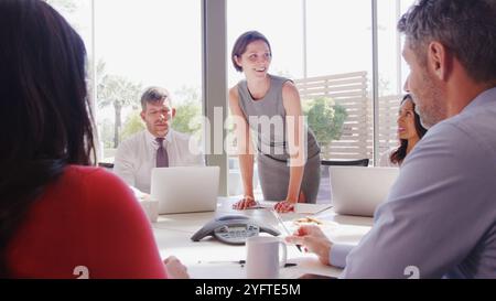 Multi-Cultural Business Team Meeting Sitting Around Table In Modern Open Plan Office Together Stock Photo