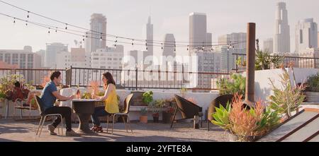 Couple Drinking Wine On Rooftop Terrace With City Skyline In Background Stock Photo