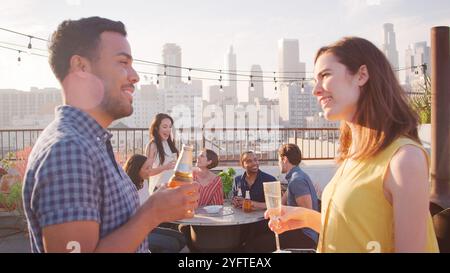 Friends Gathered On Rooftop Terrace For Drinks Party With City Skyline In Background Stock Photo