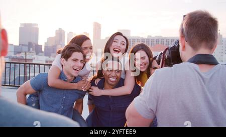 Male Photographer Photographing Group Of Friends Against Los Angeles Skyline At Sunset Stock Photo