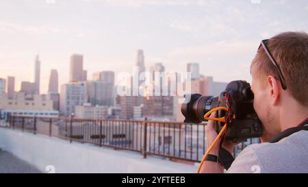 Male Photographer Taking Picture Of Los Angeles Skyline At Sunset Stock Photo