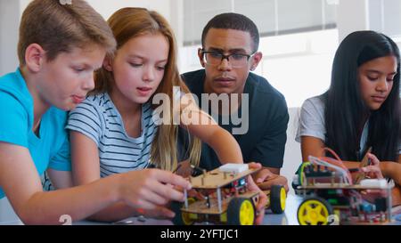 Students With Male Teacher In School Computer Class Building And Programming Robot Vehicle Stock Photo