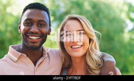 A couple enjoys a joyful moment in a sunny outdoor park. Stock Photo