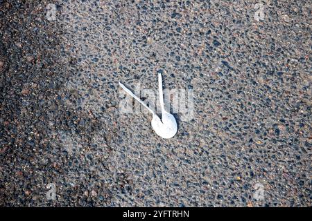There are two white plastic spoons that are laying on the ground Stock Photo