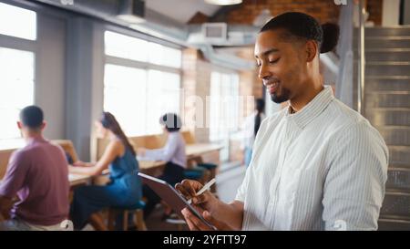 Businessman Using Digital Tablet And Stylus Pen Working In Office With Colleagues In Background Stock Photo