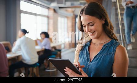 Businesswoman Using Digital Tablet Working In Busy Modern Office With Colleagues In Background Stock Photo