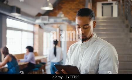 Businessman Using Digital Tablet And Stylus Pen Working In Office With Colleagues In Background Stock Photo