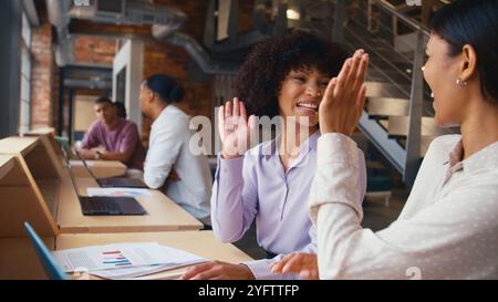 Two Businesswomen Meeting In Office Giving Each Other High Five Discussing Documents Stock Photo