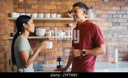 Businessman And Businesswoman Taking Coffee Break In Kitchen Area Of Modern Office Together Stock Photo