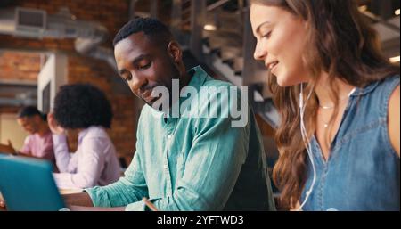 Male And Female Businesspeople Meeting In Office Working On Laptop With Colleagues In Background Stock Photo