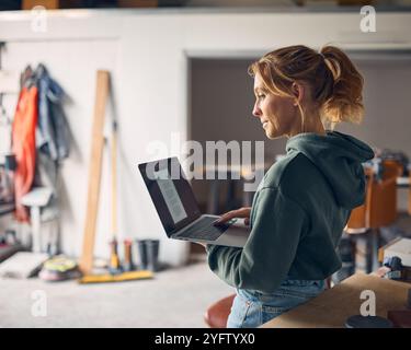 Female Worker In Concrete Workshop Using Laptop Computer Stock Photo