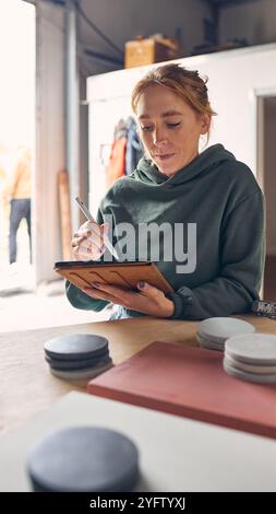 Female Worker In Concrete Workshop Using Digital Tablet And Stylus Checking Samples Stock Photo