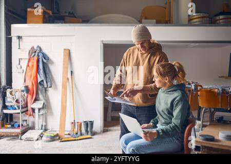Male And Female Workers Meeting In Concrete Workshop With Laptop Computer Discussing Documents Stock Photo
