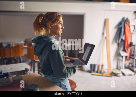 Female Worker In Concrete Workshop Using Laptop Computer Stock Photo