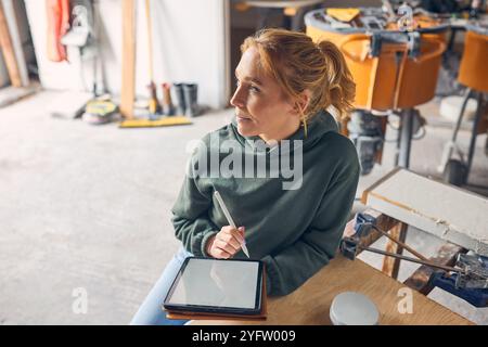 Female Worker In Concrete Workshop Using Digital Tablet And Stylus Stock Photo