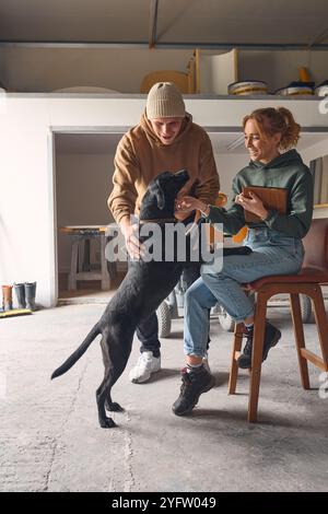 Male And Female Workers With Dog Meet In Concrete Workshop With Digital Tablet Discussing Documents Stock Photo