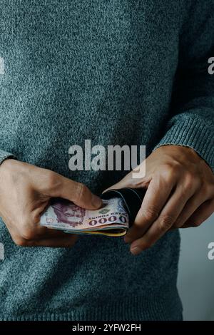 a man takes out or puts some hungarian forint bills into his wallet, indoors Stock Photo