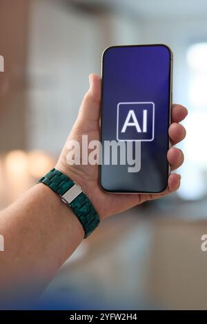 A hand prominently holds a smartphone featuring an artificial intelligence interface on its screen. The background showcases a contemporary kitchen en Stock Photo