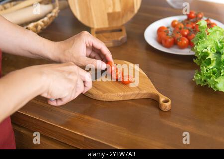 person cutting cherry tomatoes on cutting board Stock Photo