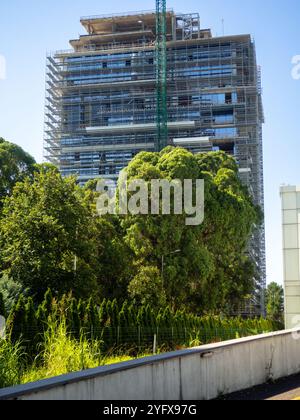 Construction of a high-rise building in a park. Exterior of a modern apartment building. Windows and bushes. Landscaping in courtyards. House facade Stock Photo