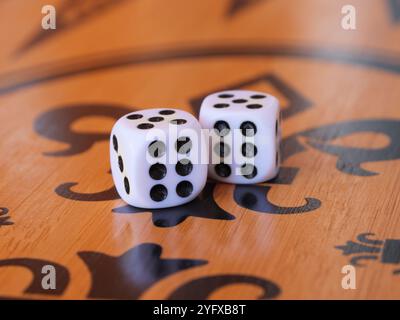 Two white dice sit on an ornate wooden board, showing double six combination with black dots. Stock Photo
