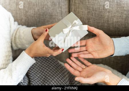 Close up of a girl giving a gift to her boyfriend for Christmas or Valentine's Day Stock Photo