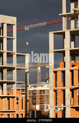 High-rise buildings under construction, featuring unfinished concrete and brick structures. While intense fighting continues in eastern Ukraine, the western regions are experiencing a construction boom. Cities in western Ukraine, such as Lviv, Ivano-Frankivsk, and Uzhhorod, have become hubs of active building and infrastructure development. These areas are attracting both internally displaced people and new investors, driving demand for housing, commercial real estate, and public facilities. The economic growth in the western regions contrasts sharply with the destruction and instability in th Stock Photo