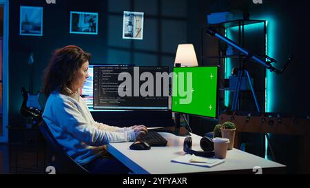 Freelancing admin using green screen computer monitors to filter malicious traffic from cybercriminals attempting to corrupt company data. IT expert in apartment working on mockup desktop PC, camera B Stock Photo