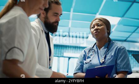 Healthcare team collaborates on human anatomy and diagnostic procedures. Group of specialists meeting in office to discuss treatment plans after radiology results. Disease prevention. Camera A. Stock Photo