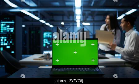 Focus on green screen laptop used by engineers in high tech data center to monitor security threats. Close up of mockup notebook used by workers ensuring compliance with regulations, camera B Stock Photo
