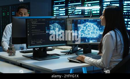 Team of engineers using AI tech on computer to do checkup in server room. Data center workers using artificial intelligence technology to process datasets for training, camera A Stock Photo